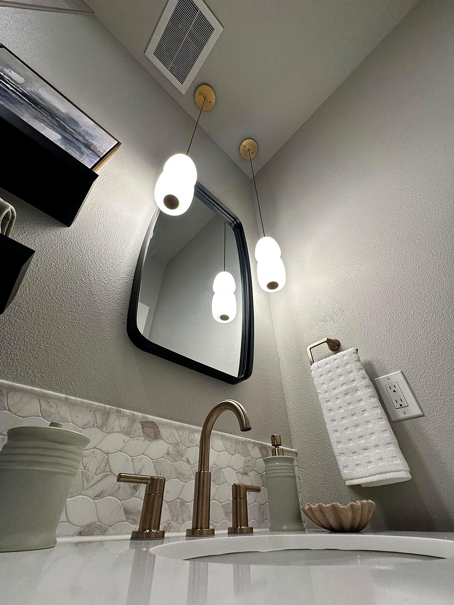 Gray bathroom with a black framed mirror and brass tapware, Austin, TX