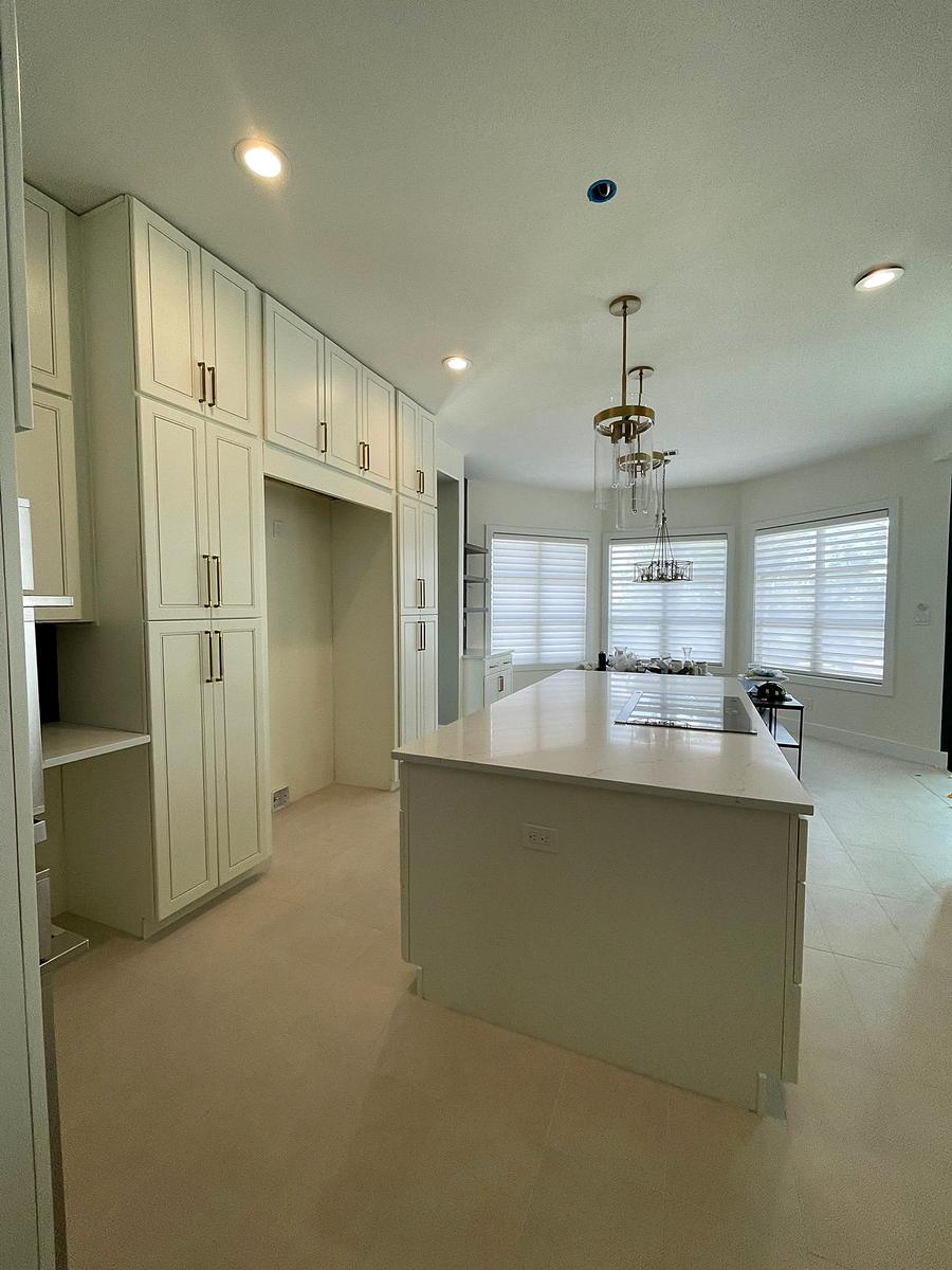 Sage green kitchen cabinetry with an island and plantation shutters, Austin, TX