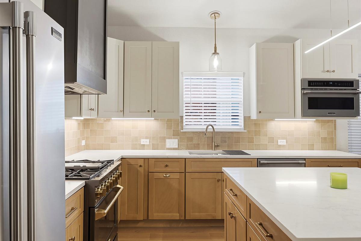 Two-tone kitchen with wood cabinetry and a gold pendant, Austin, TX